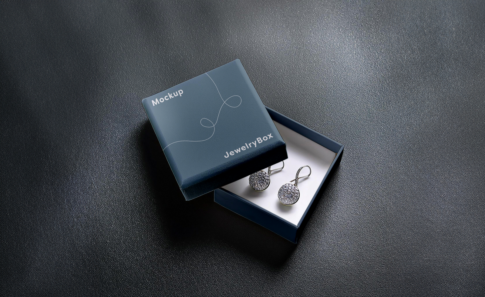 A pair of earrings in a box on a black surface psd