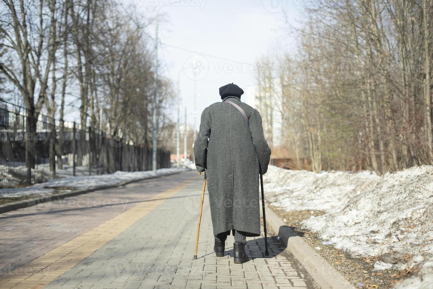 Pensioner walks down road. Elderly woman on street. Walk in Park. photo