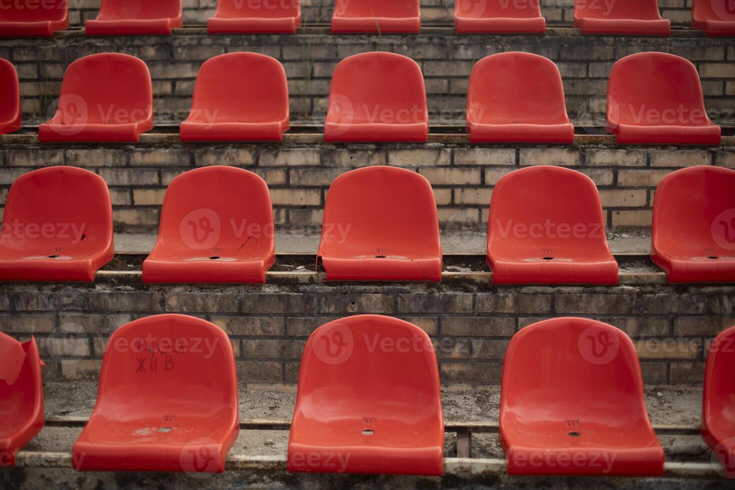 The grandstand at the sports arena. Empty seats in the stadium. Red plastic chairs. photo