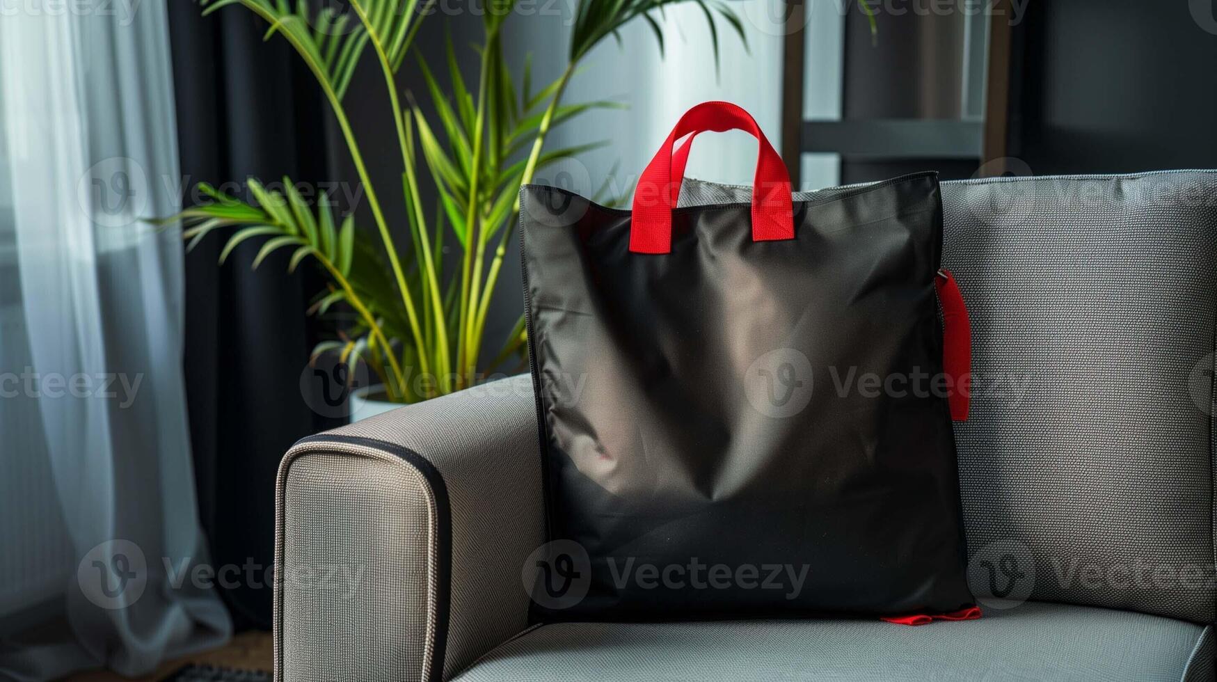Black tote bag mockup with red handles rests on cozy grey armchair, photo