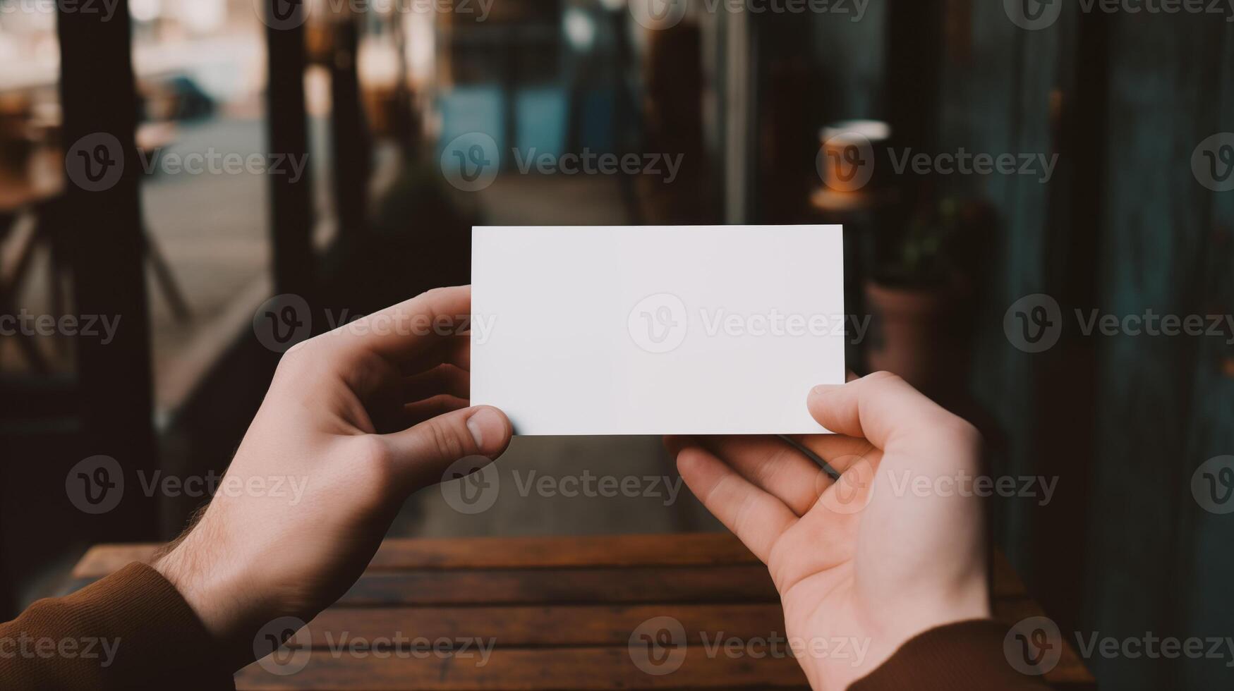 Hands displaying blank card mockup in cozy outdoor cafe. Blurred warm ambiance. Wooden table. Voucher coupon template advertising image. Businesscard mock up product photorealistic photo