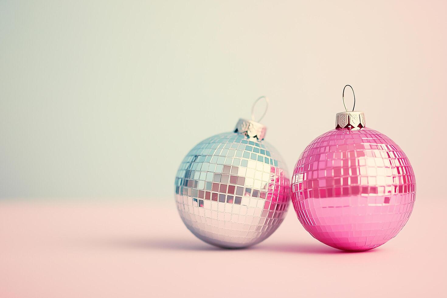 Silver and pink christmas baubles resting on a pink surface photo