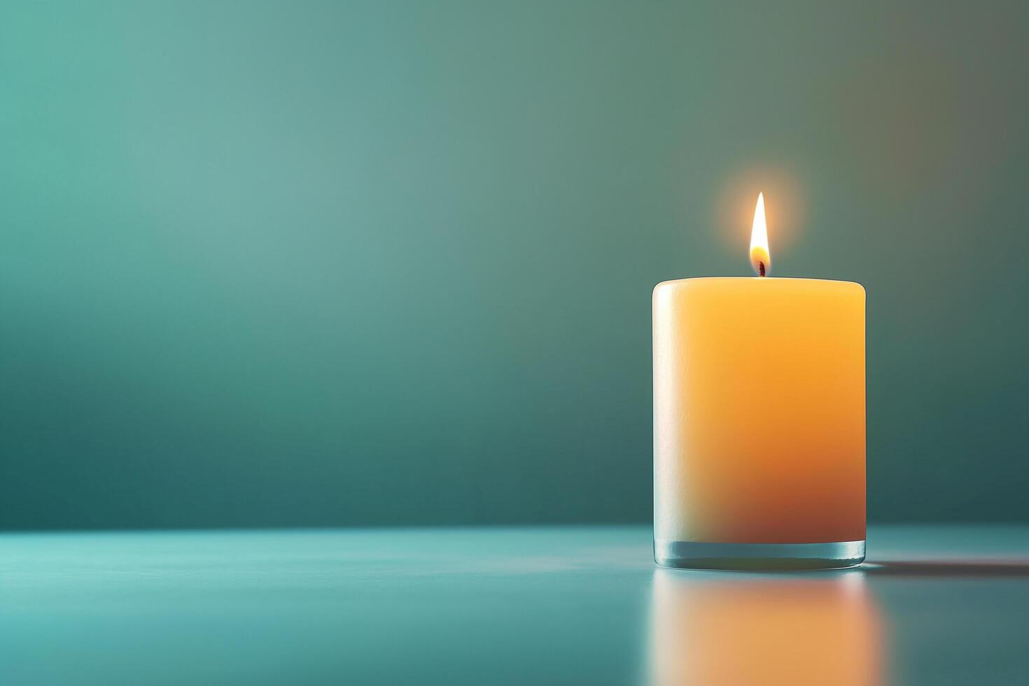 Single candle burning on table with teal background representing holidays like christmas and diwali photo