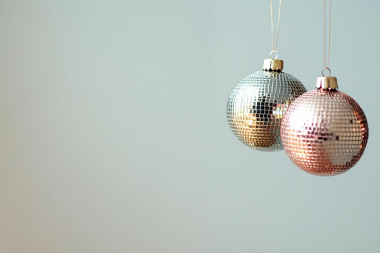 Two disco ball ornaments hanging on light blue background Christmas, New Year photo