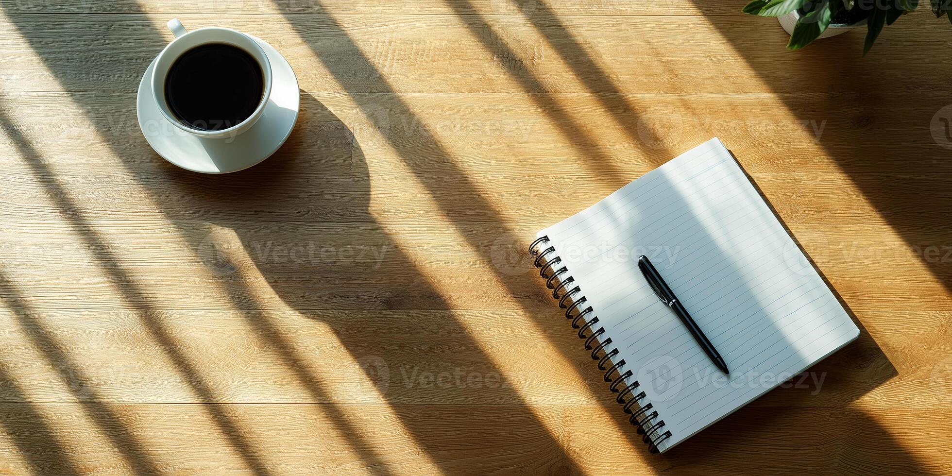 Notebook and pen sitting on desk with cup of coffee casting long shadows photo
