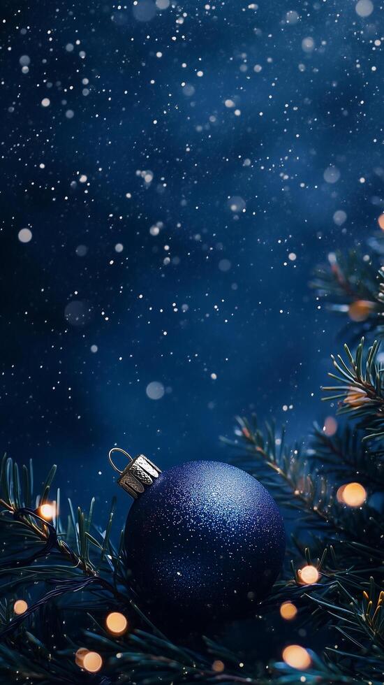 Christmas background with blue ornament hanging on snowy fir tree branch at night photo