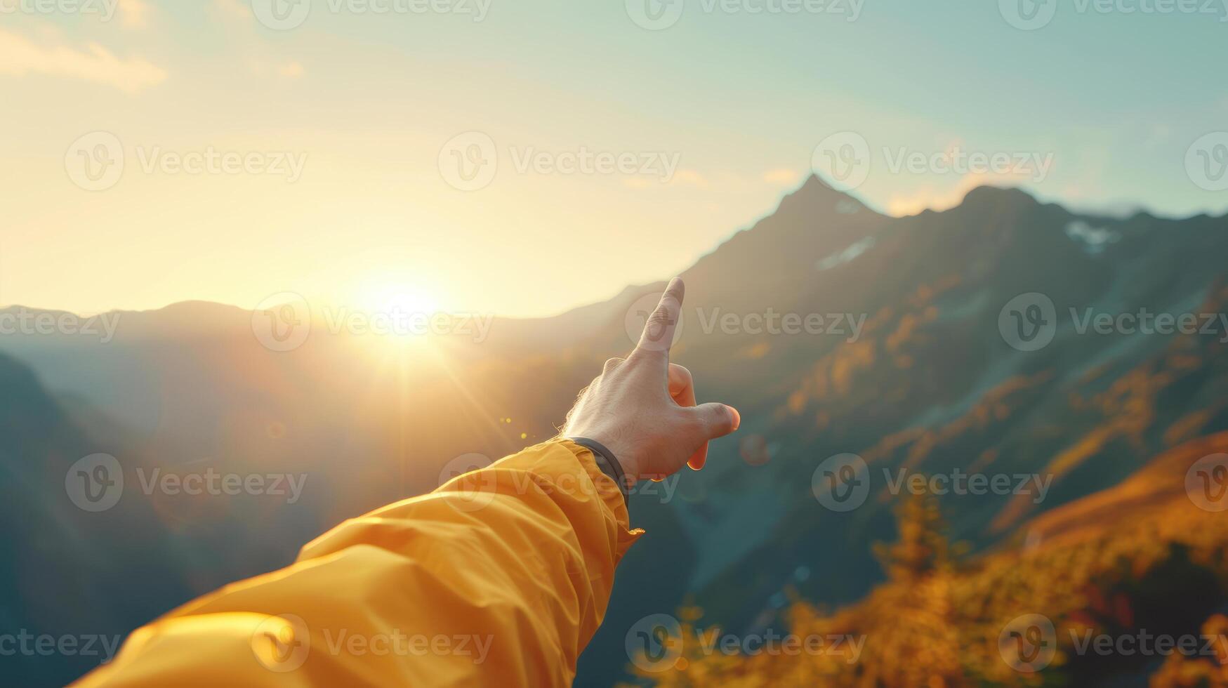 A person pointing at the sun in the mountains photo