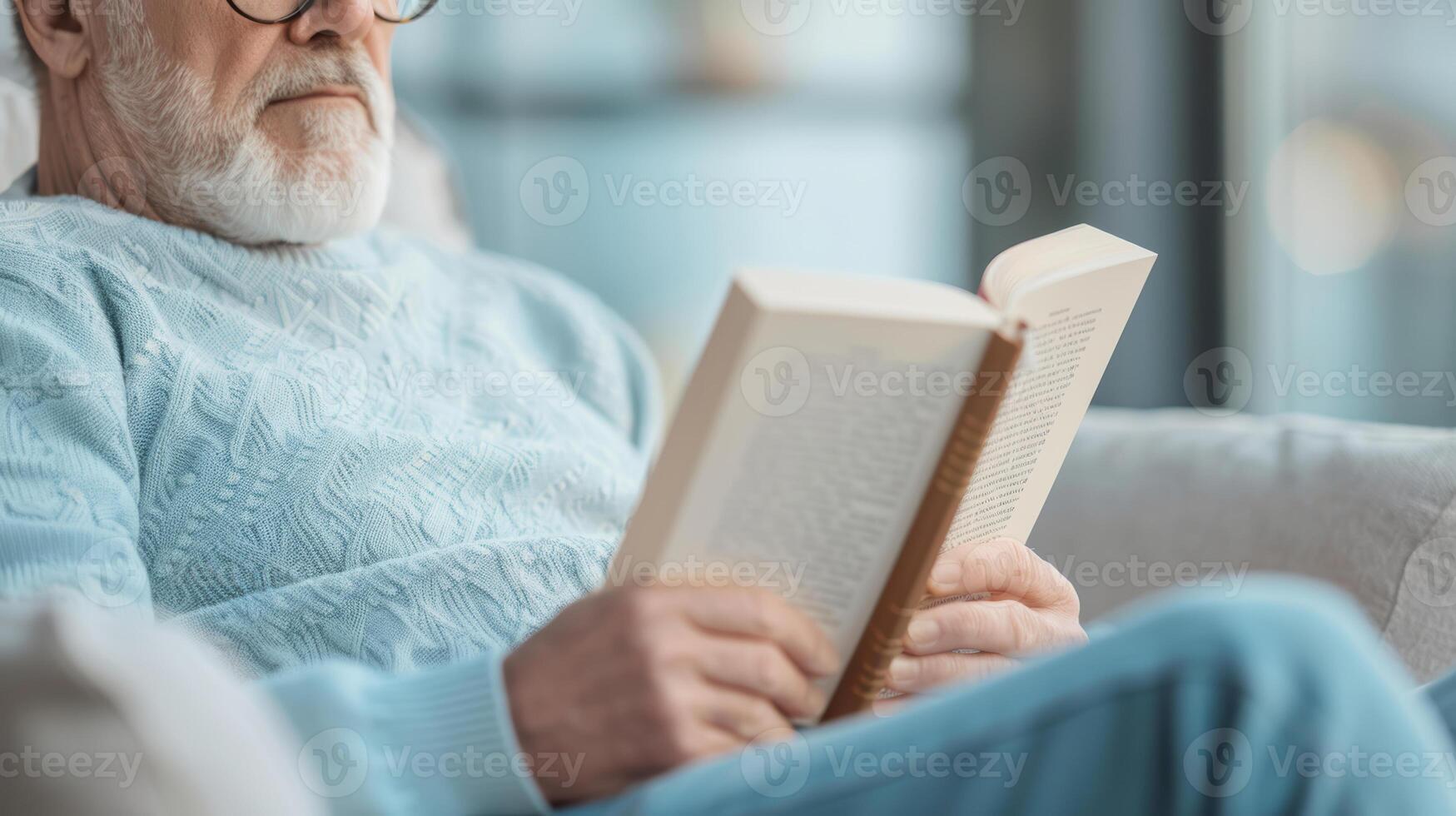 An older man with glasses and a beard reading a book photo