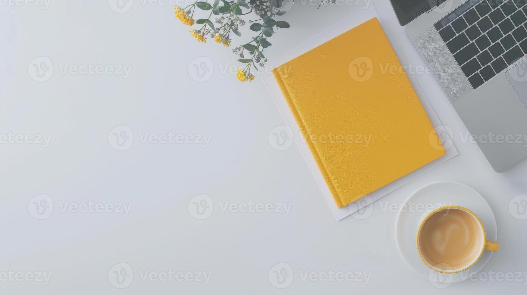 A yellow notebook, laptop and coffee cup on a white table photo