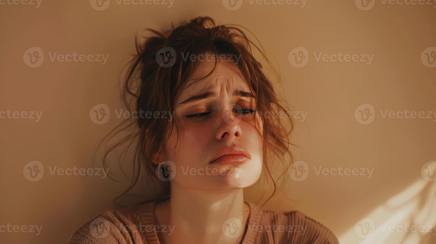 A woman is crying in front of a wall photo