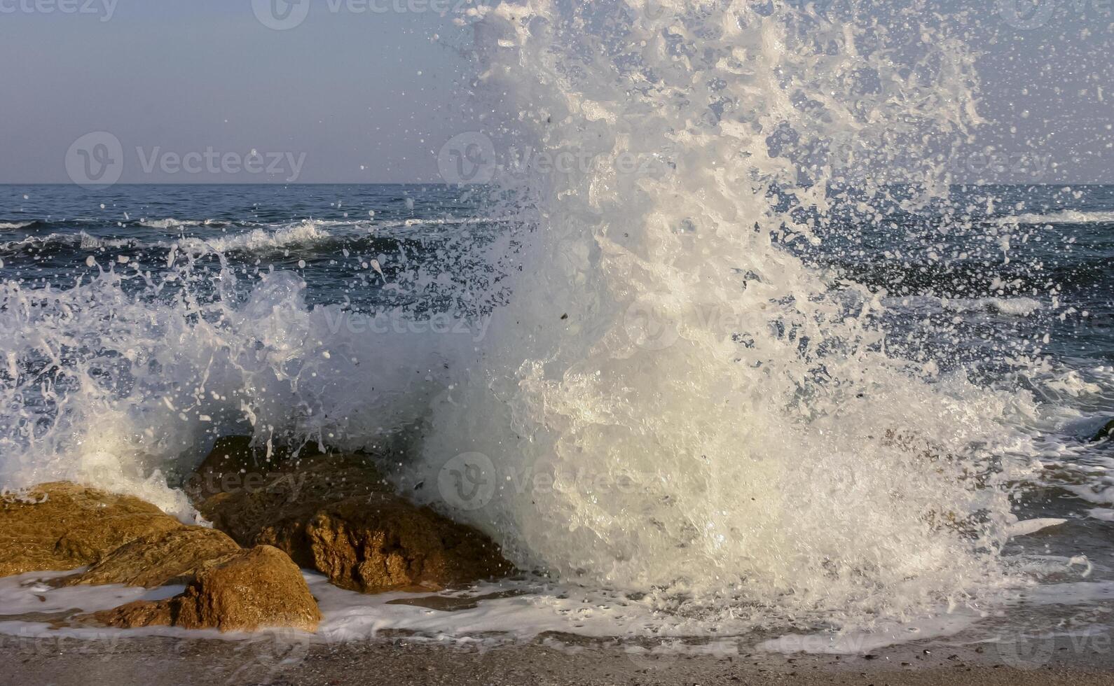 Waves break on a stone and white splashes of water fly into the air, the Black Sea photo