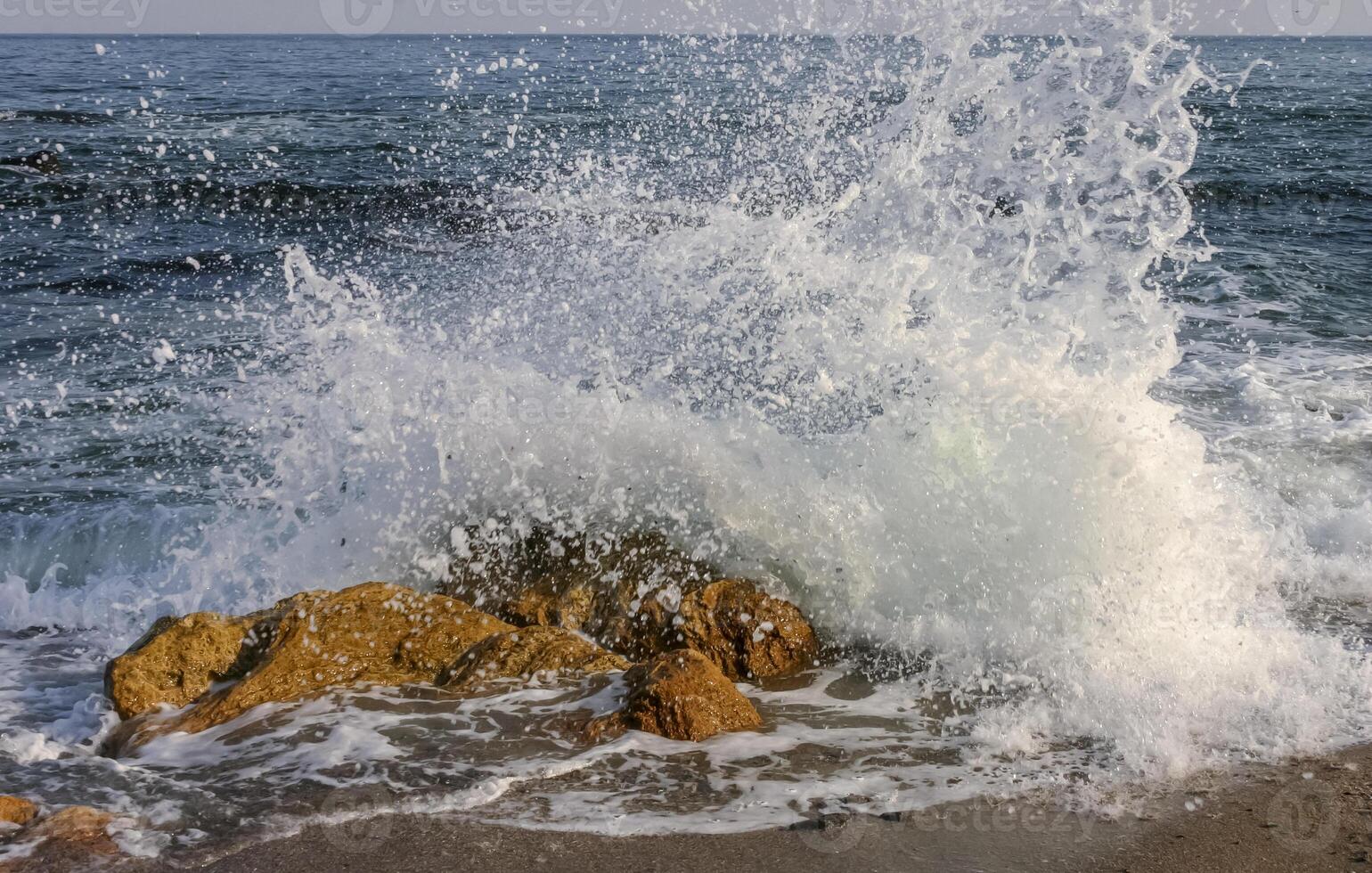 Waves break on a stone and white splashes of water fly into the air, the Black Sea photo