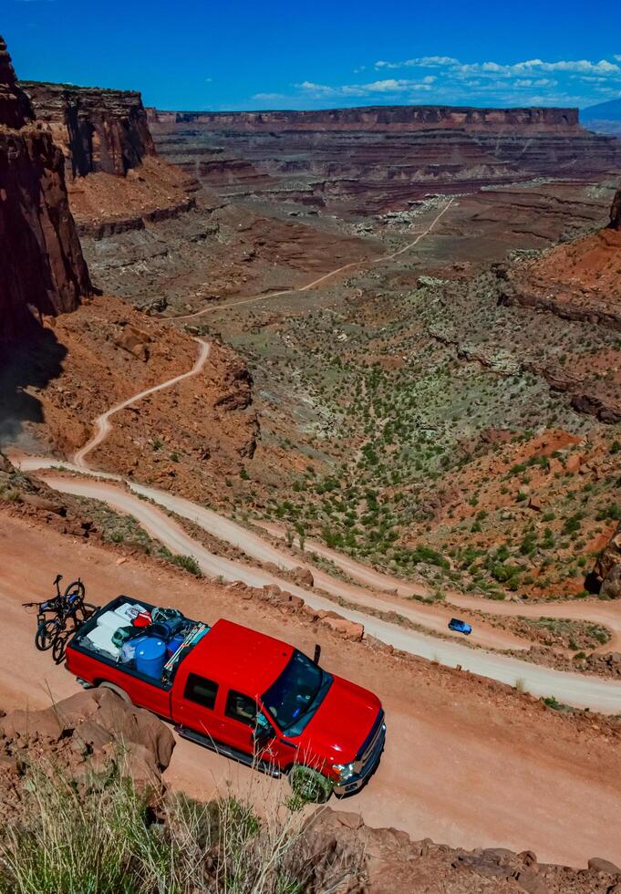 Dirt road at the bottom of the canyon among the layered geological formations of red rocks. photo