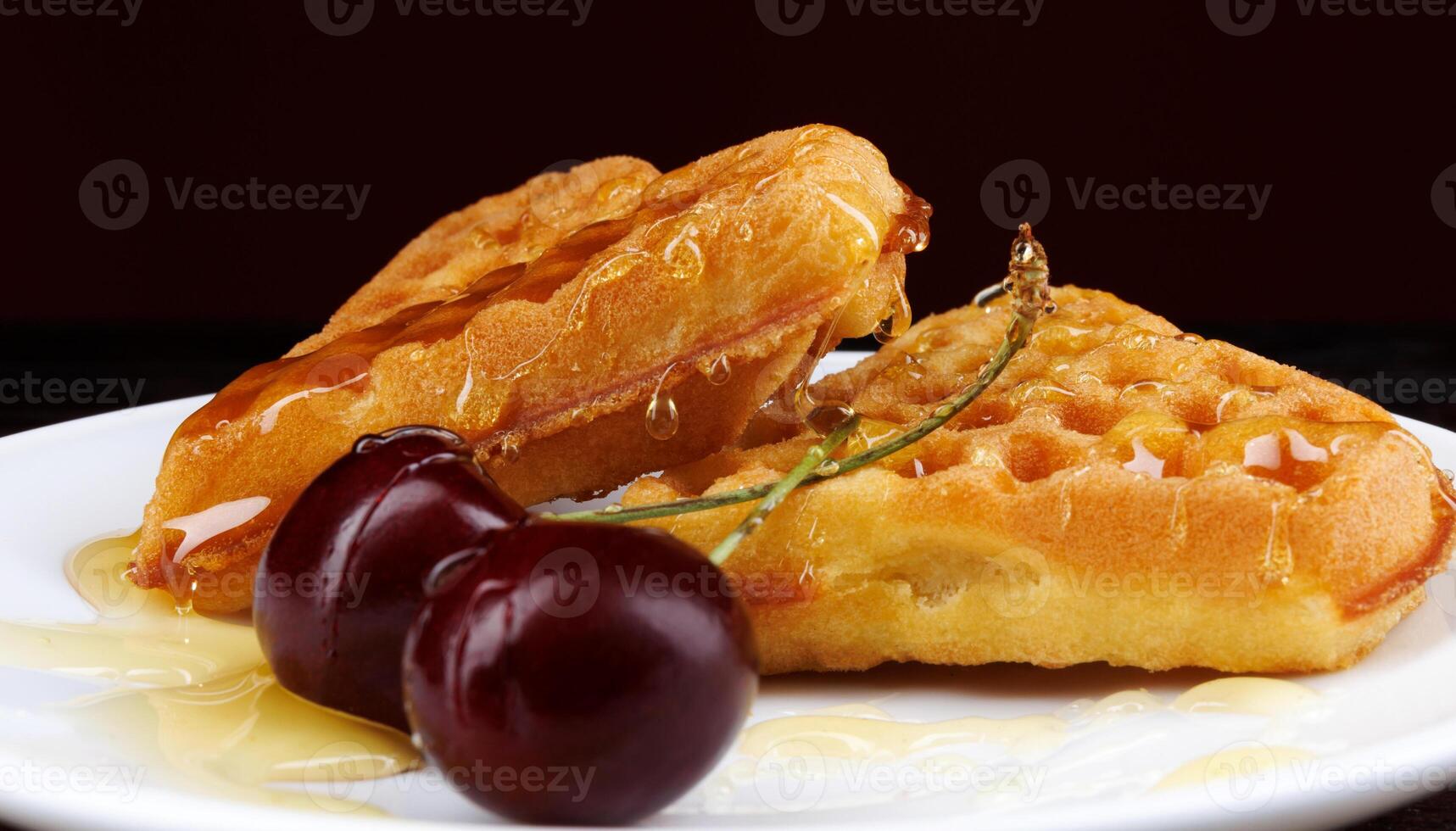 Viennese waffles with cherries lie on a white plate. Viennese waffles drizzled with honey in the shape of a heart. photo