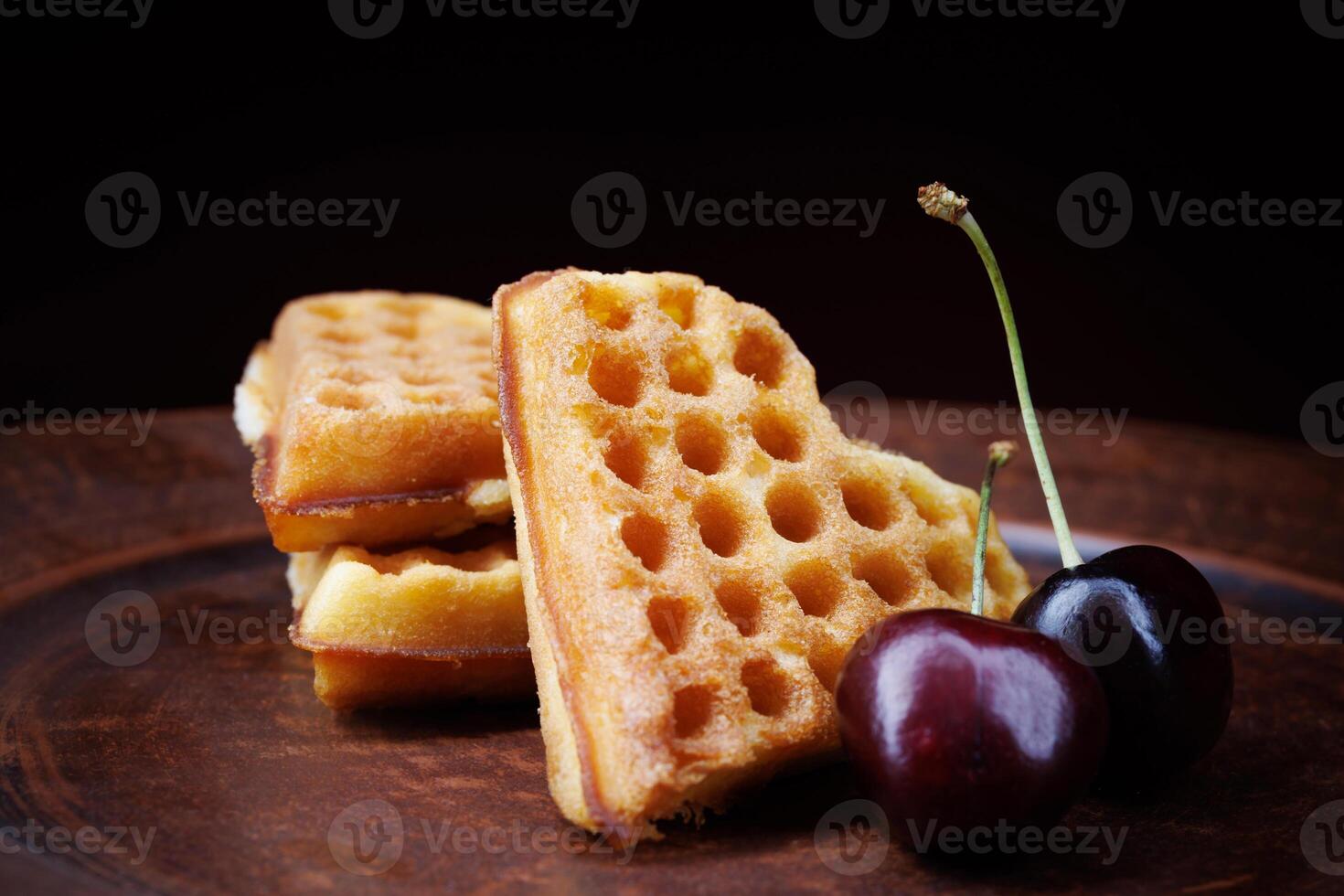 Viennese waffles in the shape of a heart lie on a clay plate. Viennese waffles with cherries. photo