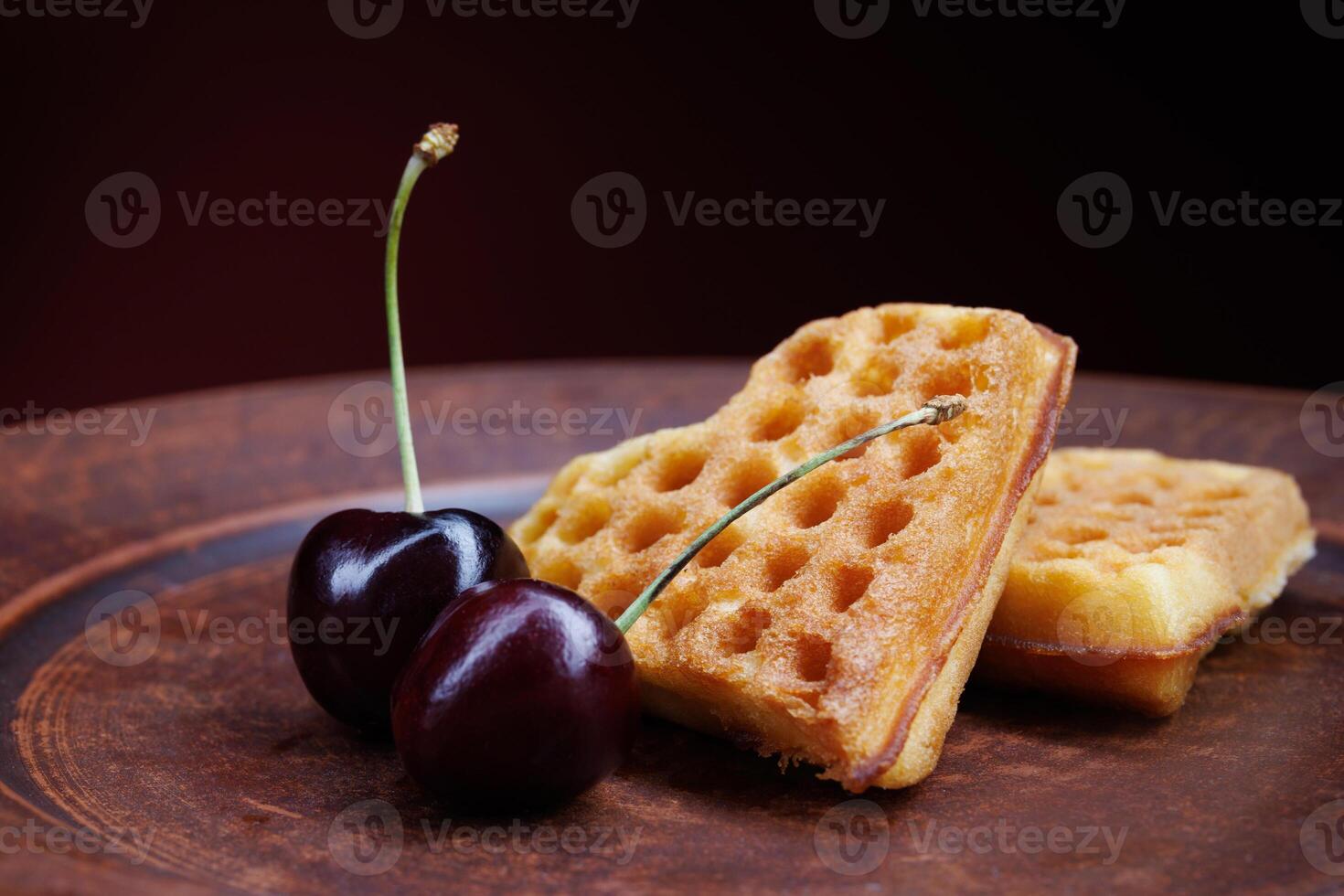 Viennese waffles in the shape of a heart lie on a clay plate. Viennese waffles with cherries. photo