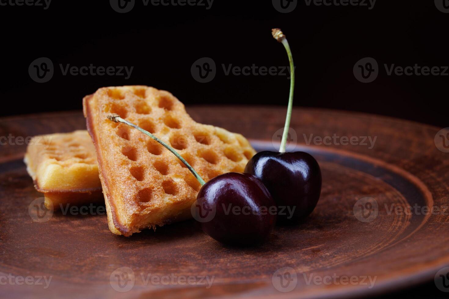 Viennese waffles in the shape of a heart lie on a clay plate. Viennese waffles with cherries. photo