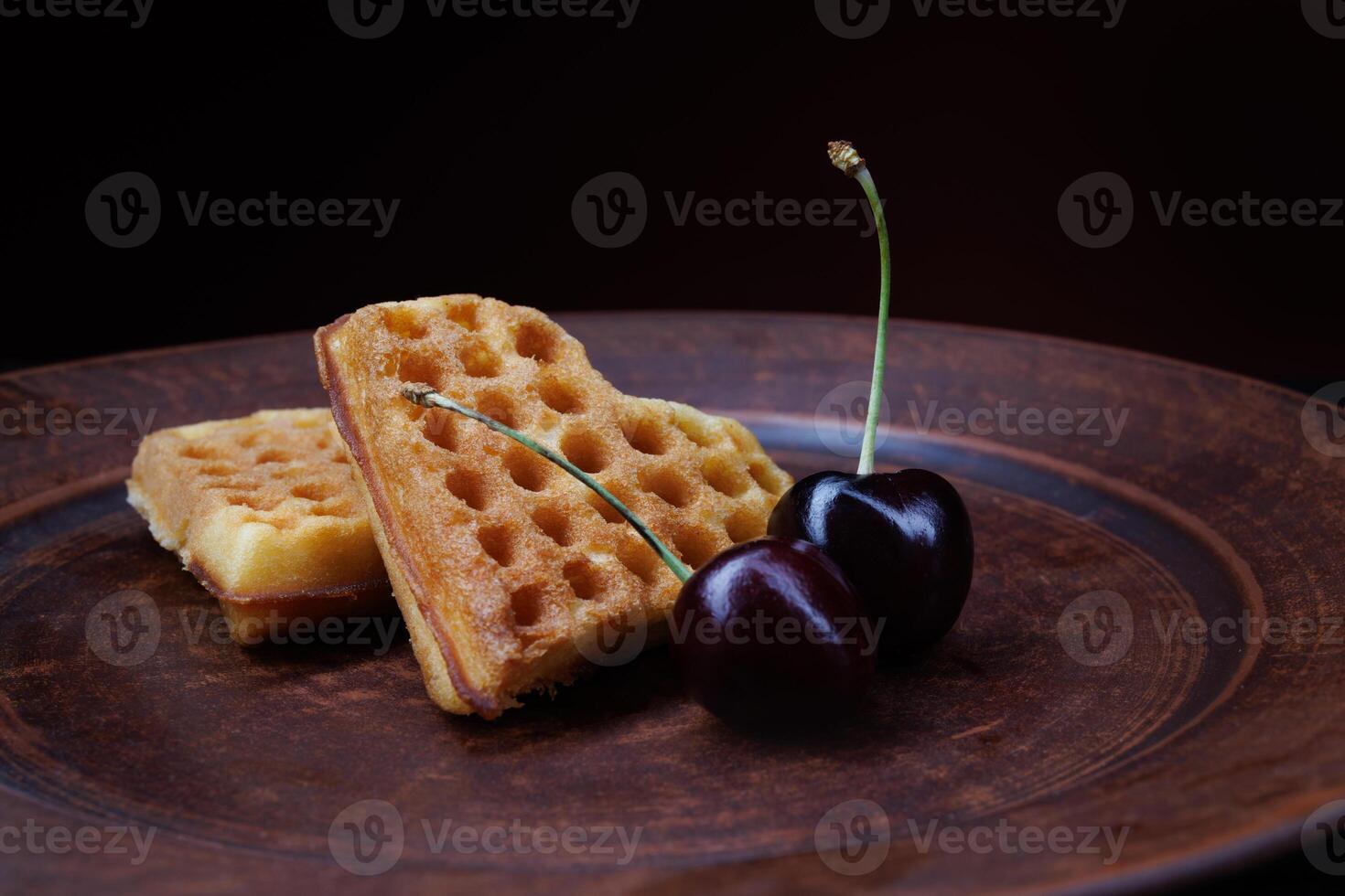 Viennese waffles in the shape of a heart lie on a clay plate. Viennese waffles with cherries. photo