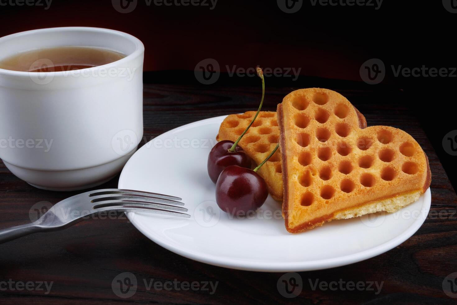 Viennese waffles with cherries lie on a white plate. Viennese waffles in the shape of a heart. photo