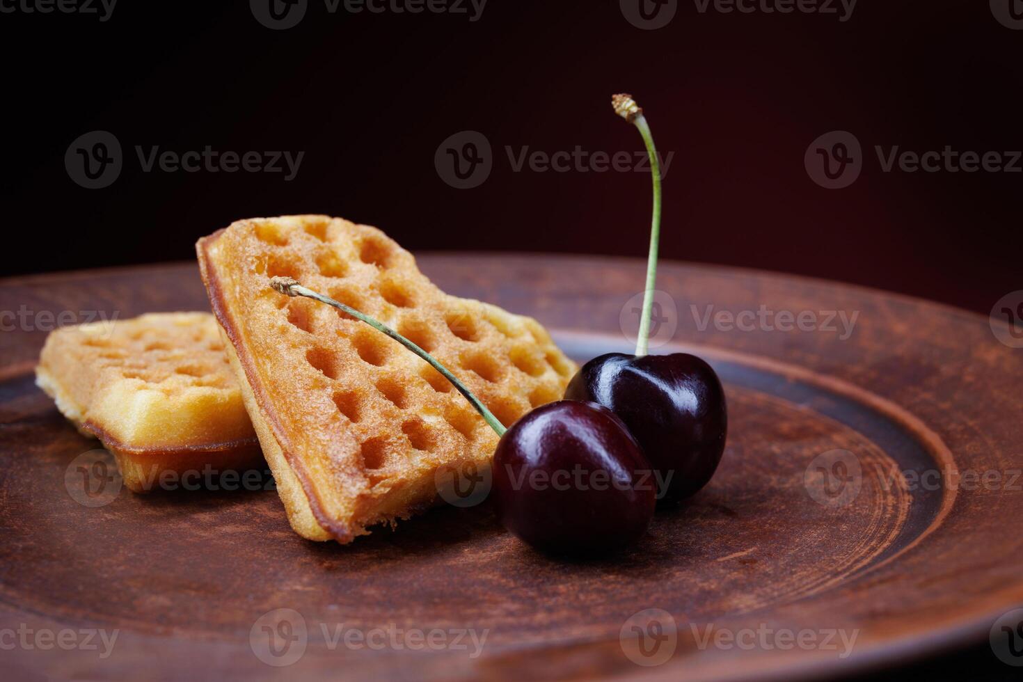 Viennese waffles in the shape of a heart lie on a clay plate. Viennese waffles with cherries. photo