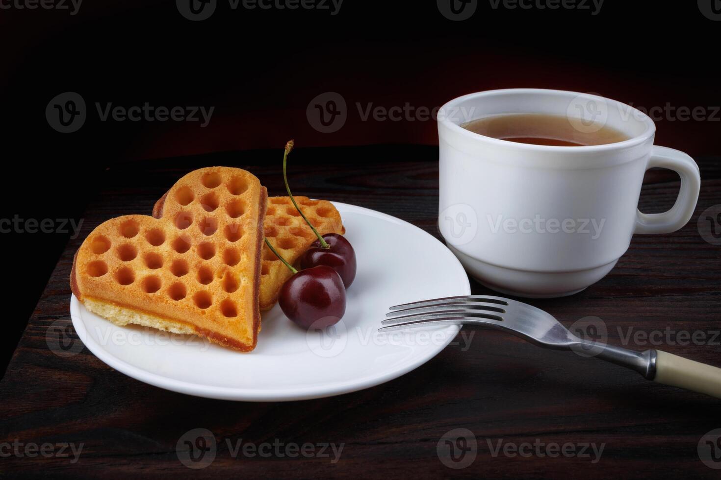 Viennese waffles with cherries lie on a white plate. Viennese waffles in the shape of a heart. photo