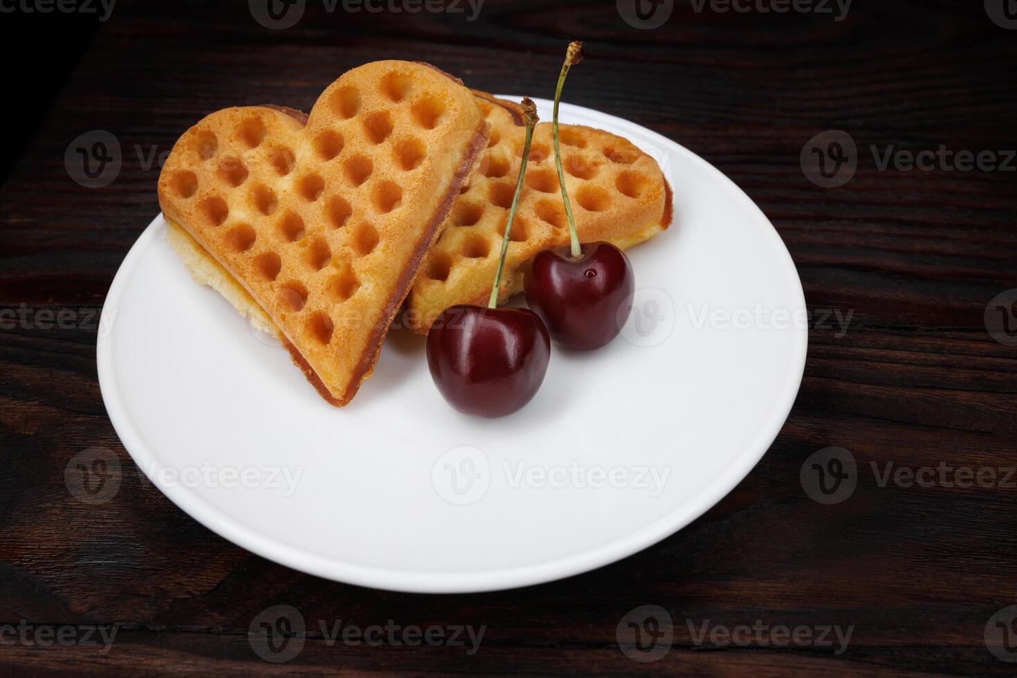Viennese waffles with cherries lie on a white plate. Viennese waffles in the shape of a heart. photo