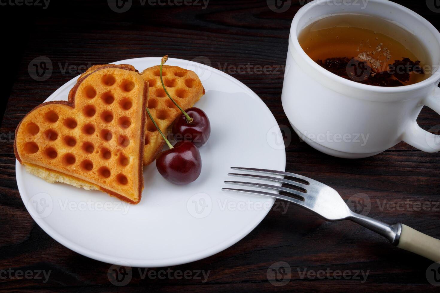 Viennese waffles with cherries lie on a white plate. Viennese waffles in the shape of a heart. photo