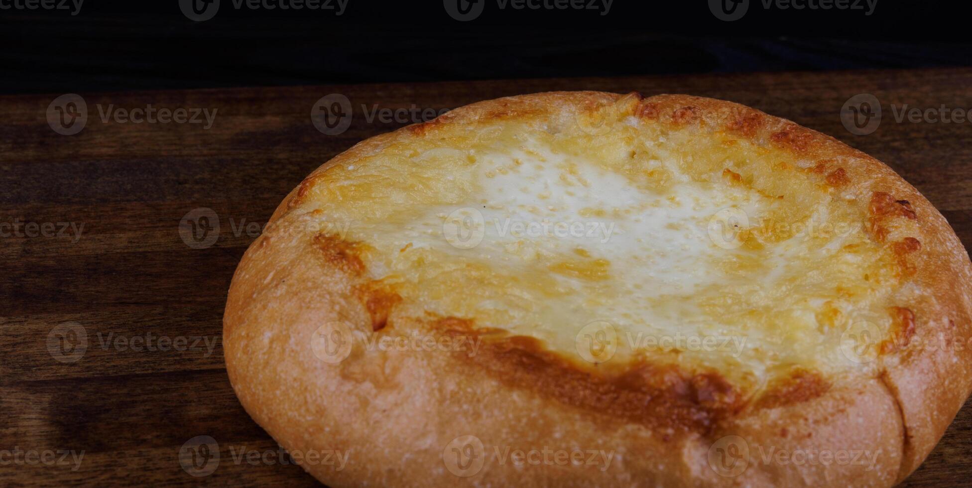 Khachapuri. Pie with cheese on a wooden background. Cheese bun. photo