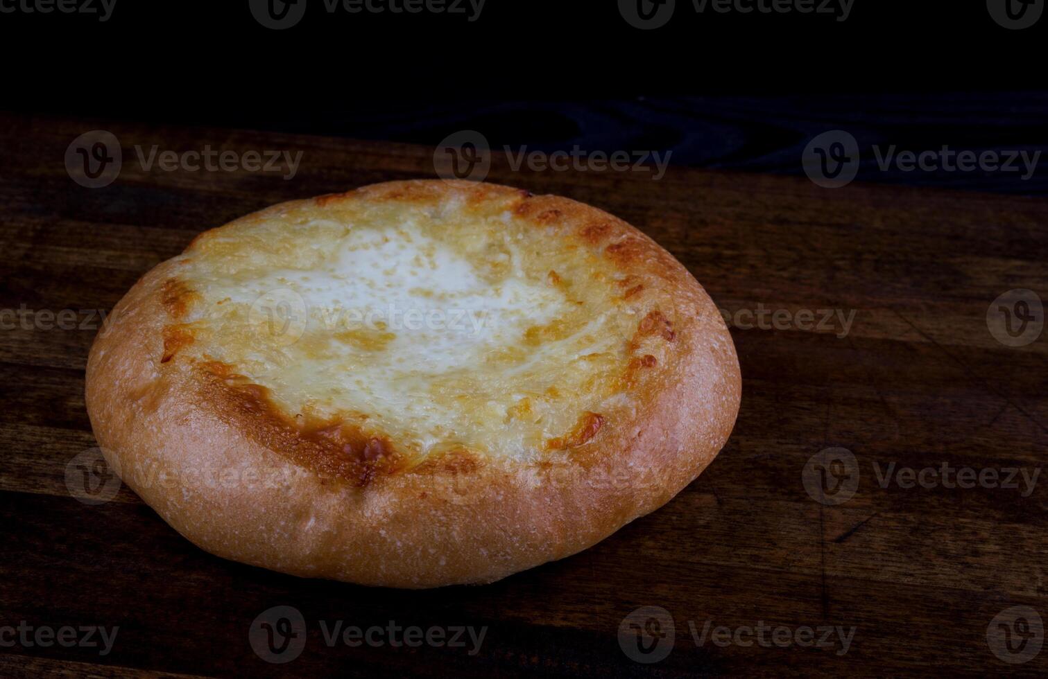 Khachapuri. Pie with cheese on a wooden background. Cheese bun. photo
