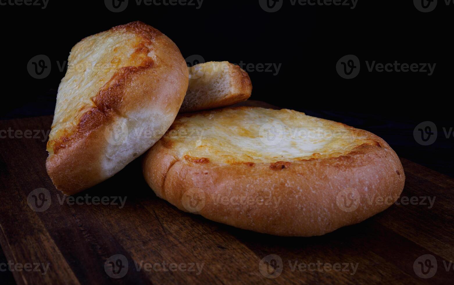 Khachapuri. Bun with cheese on a wooden background. Cheese pie. photo
