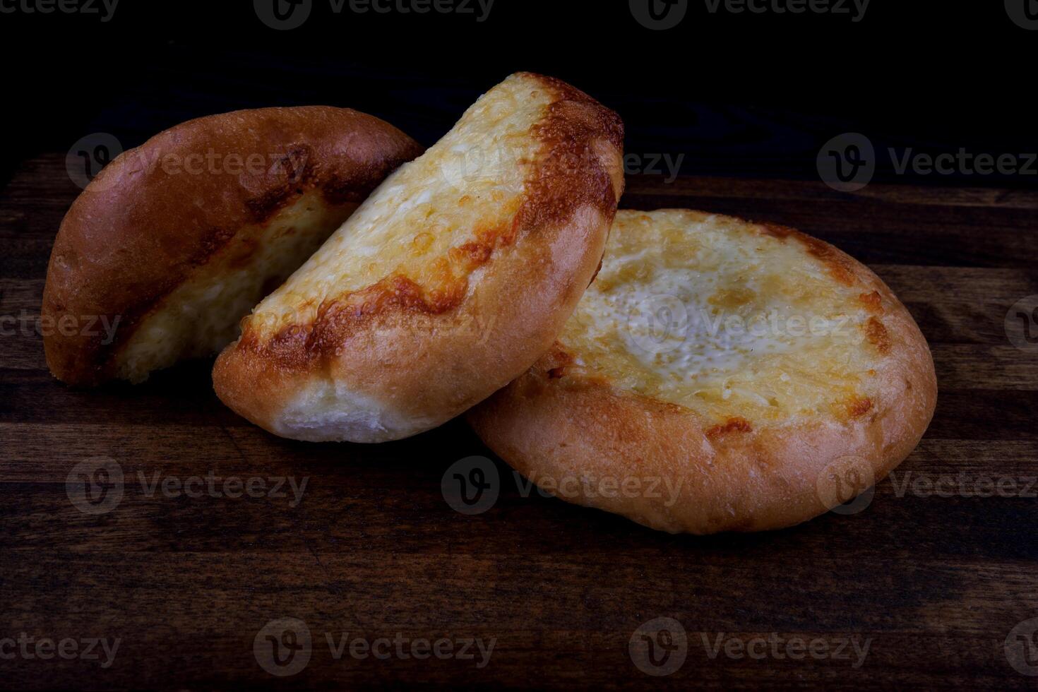 Khachapuri. Bun with cheese on a wooden background. Cheese pie. photo