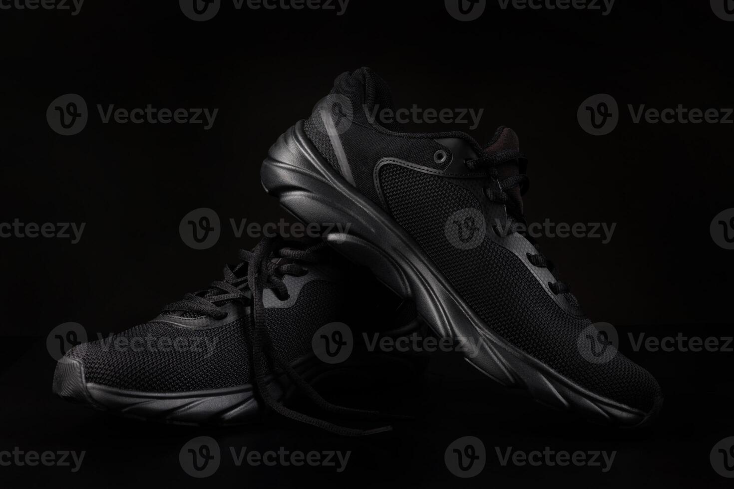 A pair of black sneakers on a black background. Beautiful black sneakers. photo