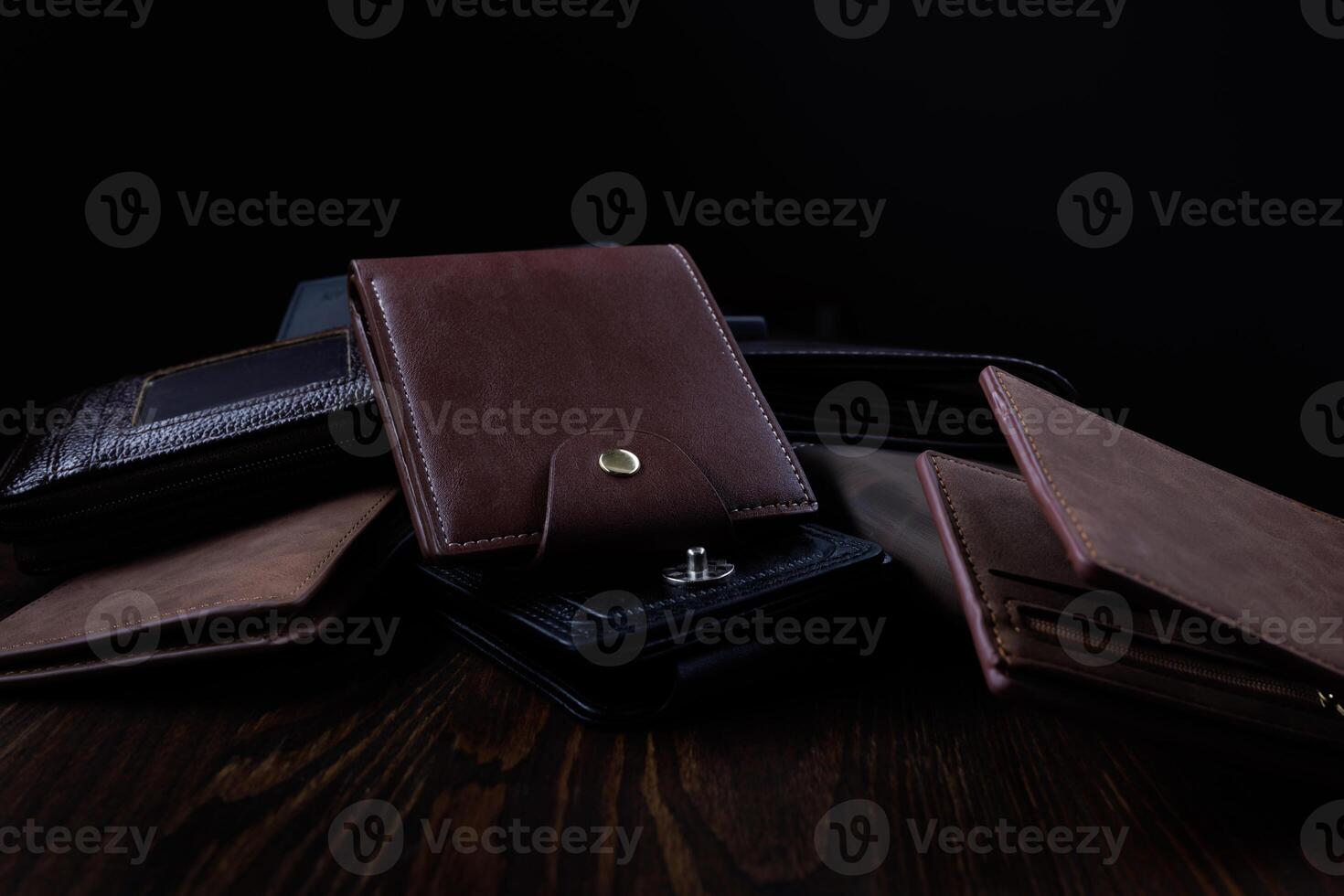 Many beautiful leather wallets lie on a wooden surface. photo