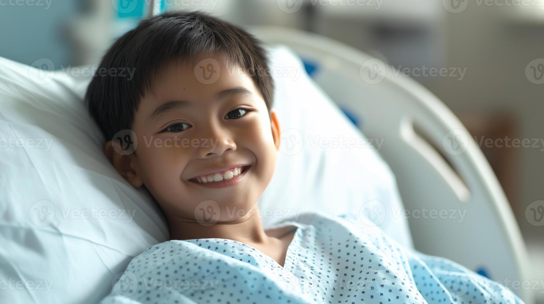 Central Asian Boy Smiling While Lying in Hospital Bed Wearing Patient Gown, Healthcare and Recovery Scene photo