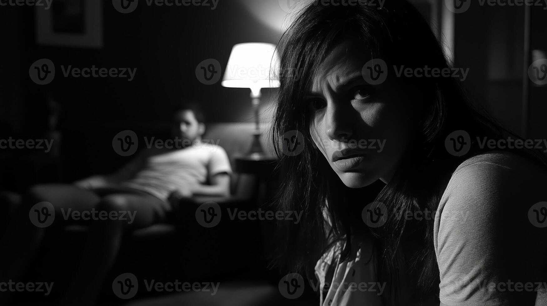 Intense Late Night Scene with Concerned Woman and Relaxed Man in Dimly Lit Room, Capturing Dramatic Emotions and Tension photo