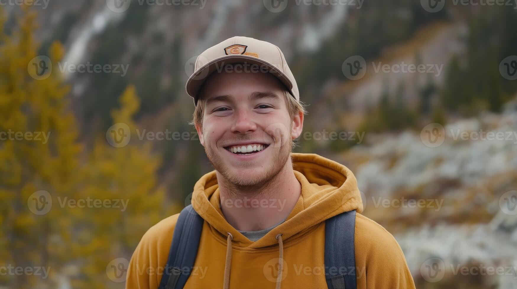 Young Man with Freckles and Baseball Cap Smiling Outdoors in Autumn Mountain Landscape Background photo