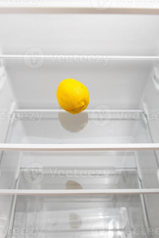 refrigerator with single lemon on glass shelf photo