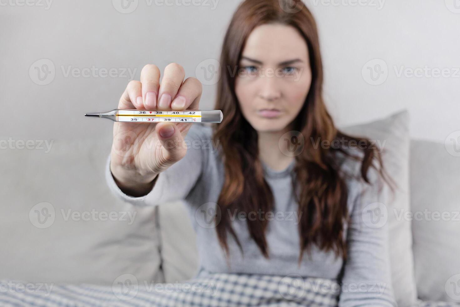 Woman caught a cold, got sick, she shows mercury thermometer with a temperature of 37,6 C. photo