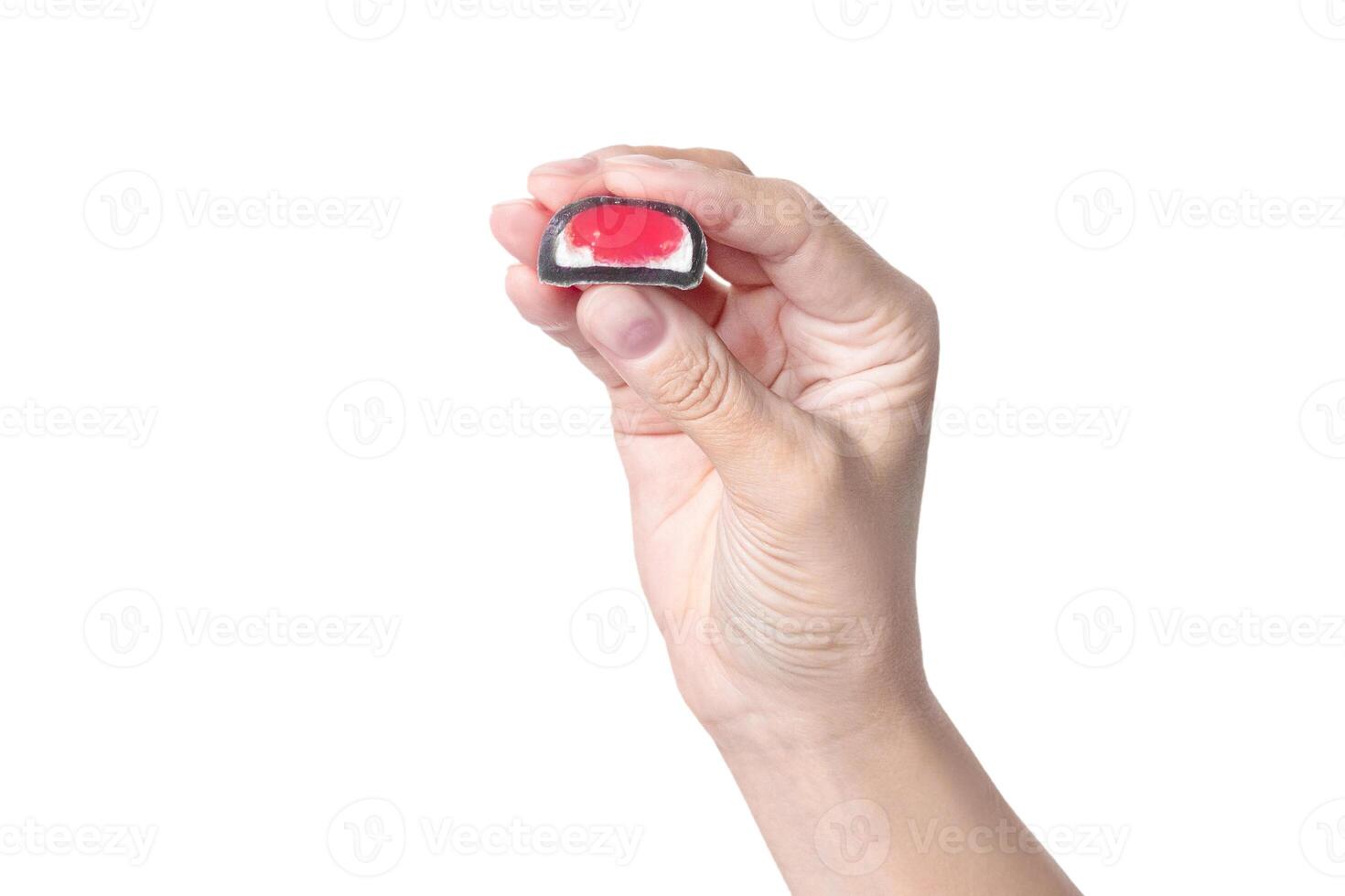 A woman's hand holds a mochi candy, shows the size and berry red filling on white background photo