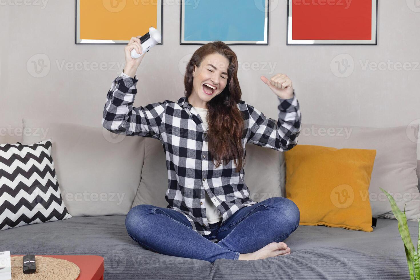 Woman rejoices in the victory in the online game on the console. She is smile, sit relax on sofa at home have fun play online game. close up photo