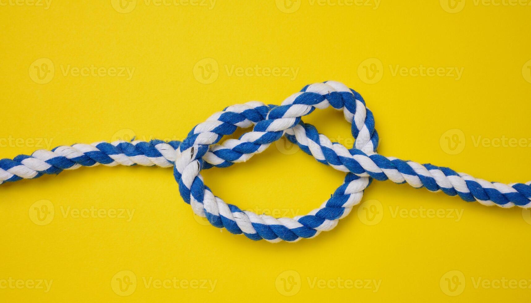 Thick blue rope tied in a knot on a yellow background photo