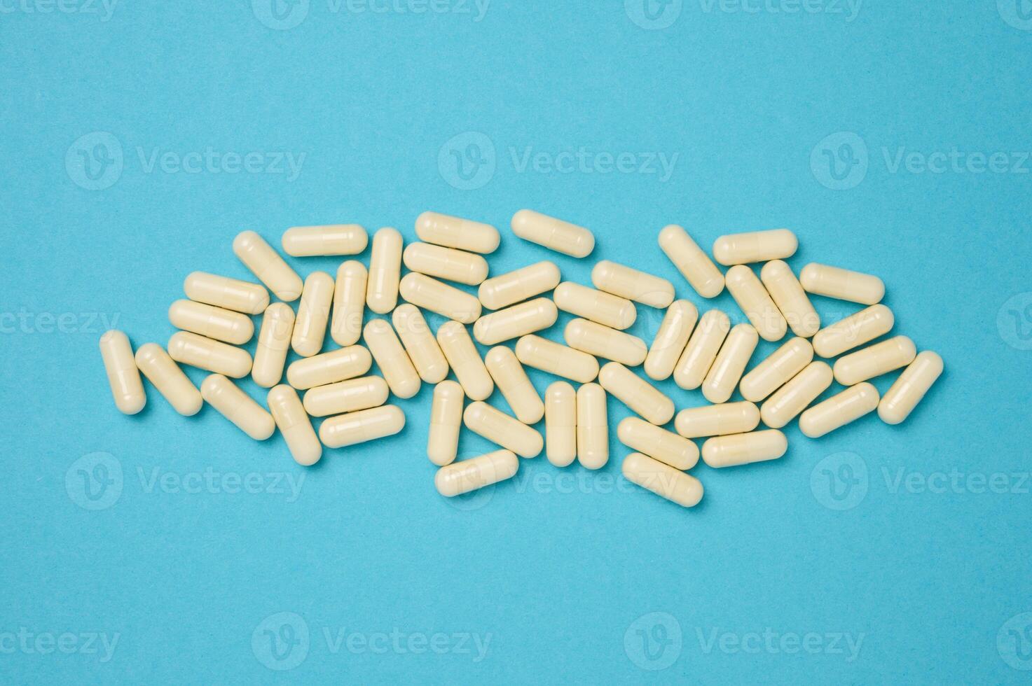 Oval white capsules on a blue background. Medical pills, top view photo