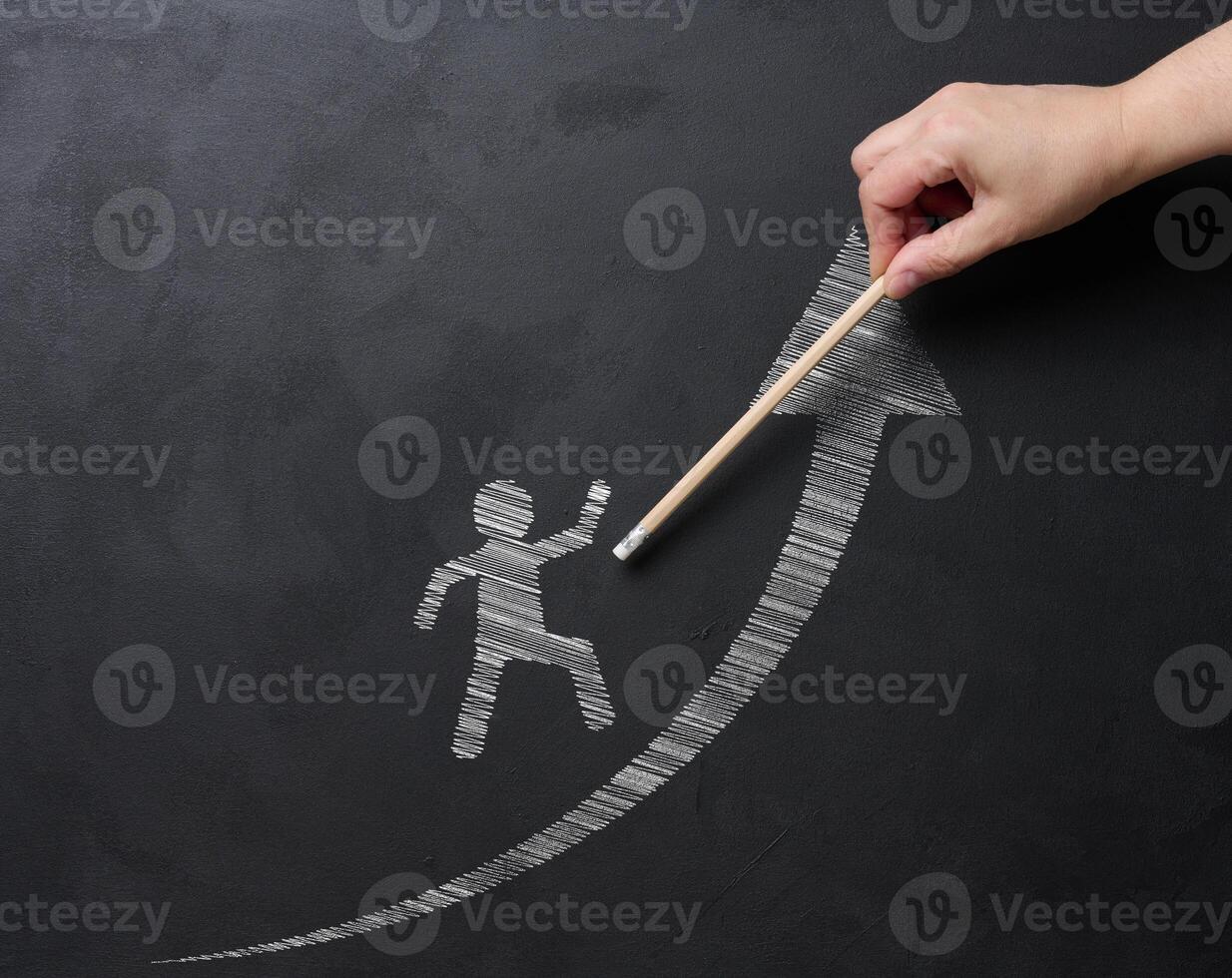 A hand draws a picture of a person walking on an upward arrow on a blackboard with chalk, symbolizing personal growth, success and progress. Concept of development and goal achievement photo