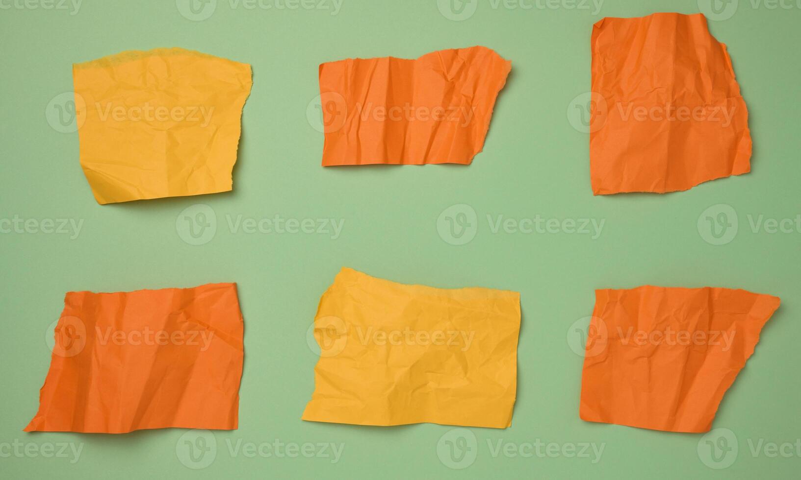 Torn pieces of yellow and orange paper on a green background photo