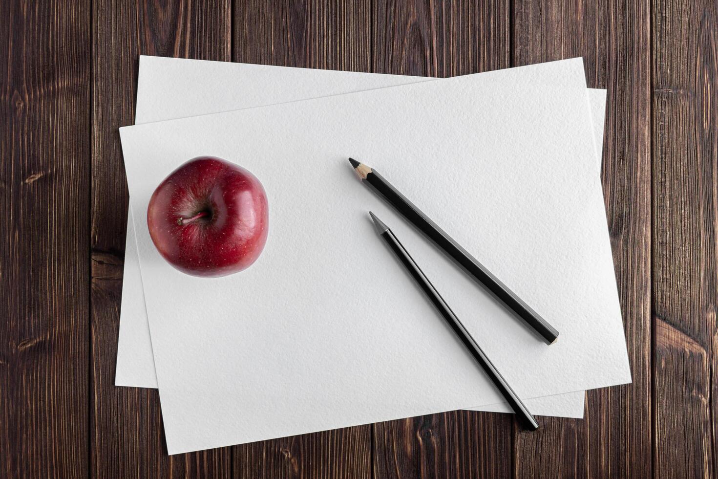 Watercolor paper mockup with red apple on wooden table. photo