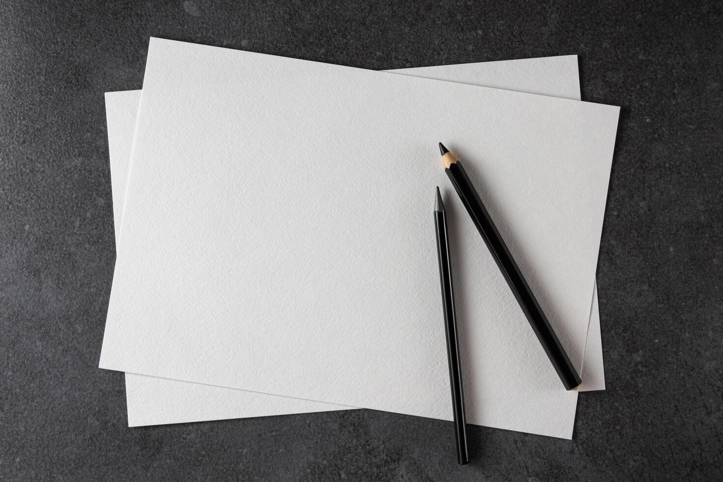 Paper mockup. Watercolor A4 paper with black pencils on dark background. photo