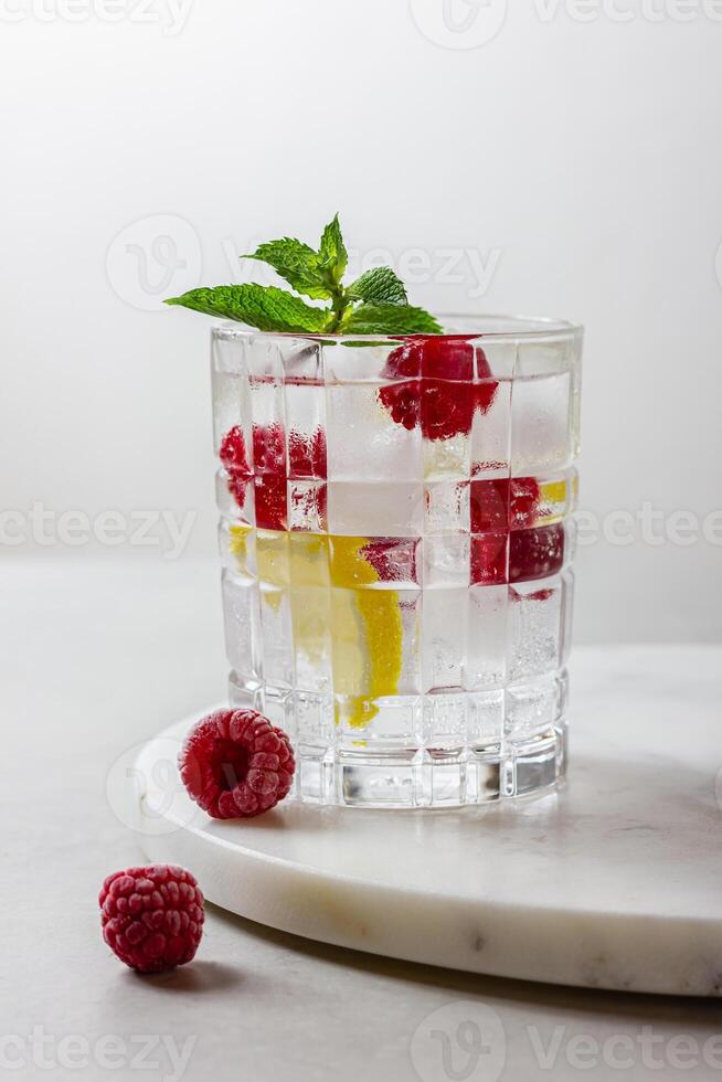 Raspberry cocktail with ice in a glass on a light background photo