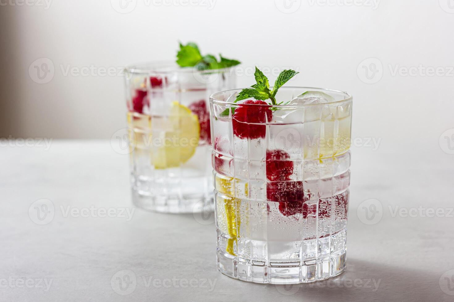 Raspberry cocktail with ice in a glass on a light background photo