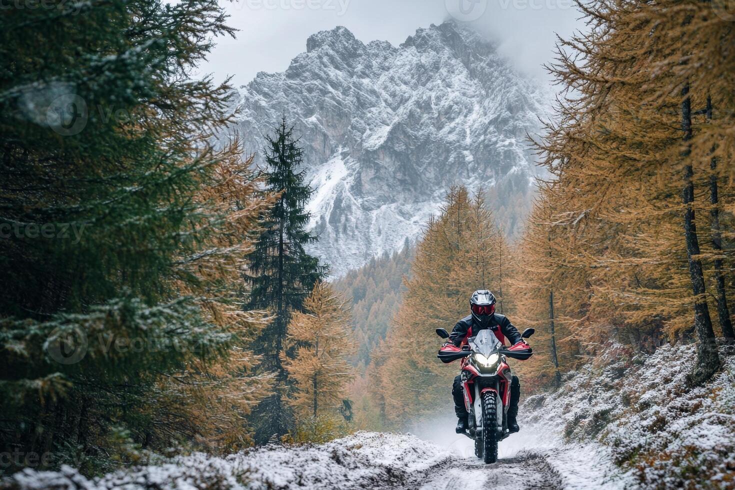 Motorcyclist riding adventure motorcycle on snowy forest path in the italian dolomites photo