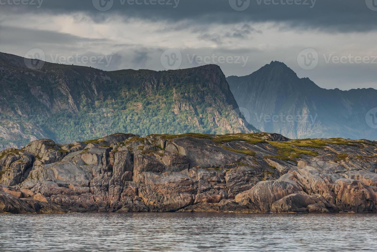Norwegian seascape, rocky coast with dramatic skies, the sun breaks through the clouds, sheer cliffs, small islands illuminated by the sun photo